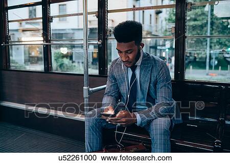 Businessman using smartphone on tram in city View Large Photo Image Stock Image - Businessman using smartphone on tram in city. Fotosearch