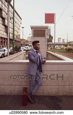 Businessman using smartphone, smoking on pavement, Milano, Lombardia, Italy View Large Photo Image Stock Image - Businessman using smartphone, smoking on pavement, Milano, Lombardia, Italy. Fotosearch