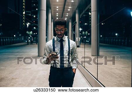 Businessman using smartphone, walking past mirrored wall of office building, Milano, Lombardia, Italy View Large Photo Image Stock Image - Businessman using smartphone, walking past mirrored wall of office building, Milano, Lombardia, Italy. Fotosearch