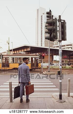 Stock Photo - Businessman waiting by pedestrian crossing, Milano, Lombardia, Italy. Fotosearch