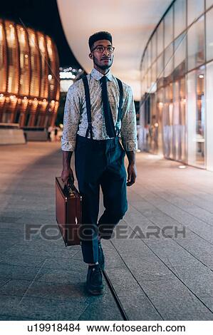 Picture - Businessman walking past buildings in city, Milano, Lombardia, Italy. Fotosearch