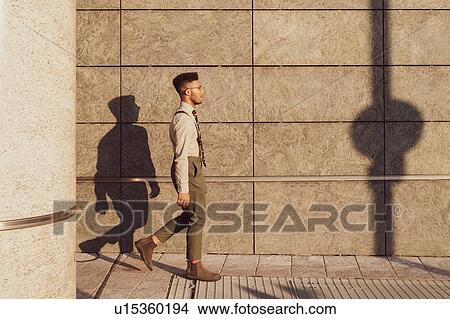 Picture - Businessman walking past concrete wall, Milano, Lombardia, Italy. Fotosearch