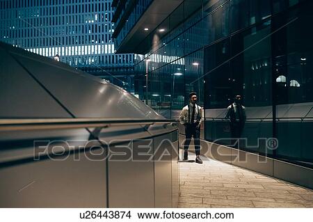 Picture - Businessman walking past mirrored wall of office building, Milano, Lombardia, Italy. Fotosearch
