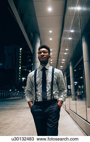 Stock Image - Businessman walking past mirrored wall of office building, Milano, Lombardia, Italy. Fotosearch