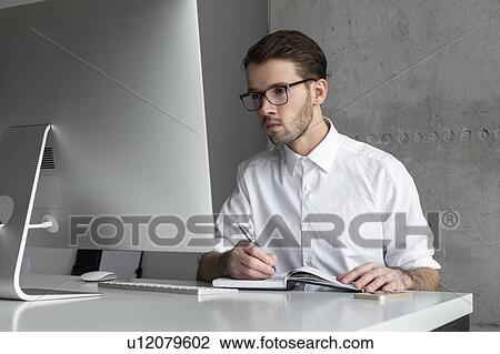 Stock Image - Businessman writing in note book. Fotosearch