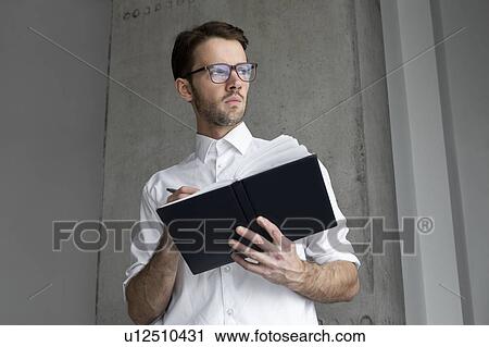 Stock Image - Businessman writing in note book. Fotosearch