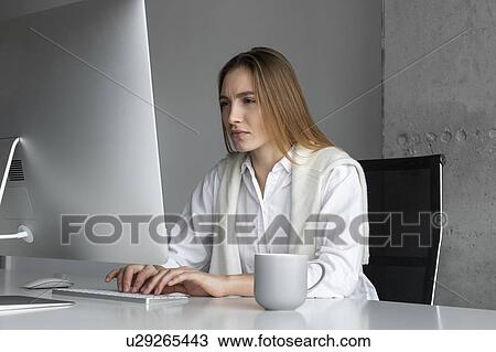 Stock Image - Businesswoman concentrating while working at computer. Fotosearch