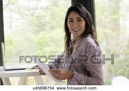 Picture - Businesswoman with papers in office. Fotosearch