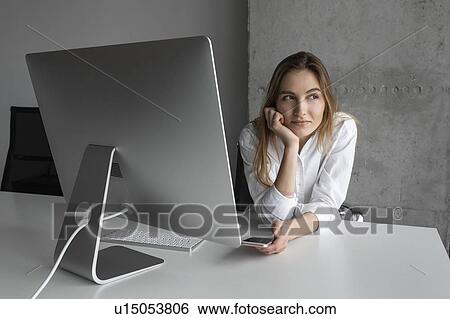 Businesswoman with smartphone day dreaming at desk View Large Photo Image Stock Photograph - Businesswoman with smartphone day dreaming at desk. Fotosearch