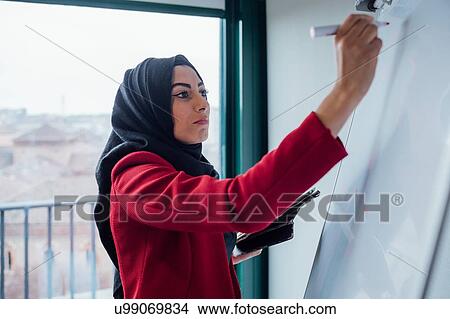 Businesswoman writing on whiteboard in office View Large Photo Image Picture - Businesswoman writing on whiteboard in office. Fotosearch