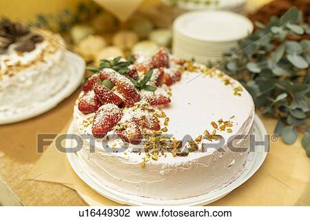 Stock Image - Cake topped with strawberries and pistachios. Fotosearch