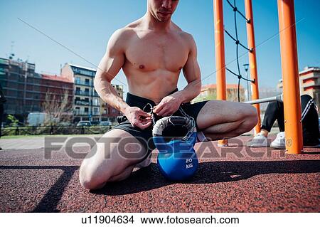 Calisthenics at outdoor gym, bare chested young man attaching kettlebell on waist harness View Large Photo Image Picture - Calisthenics at outdoor gym, bare chested young man attaching kettlebell on waist harness. Fotosearch
