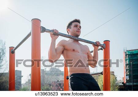 Calisthenics at outdoor gym, bare chested young man doing pull up on exercise equipment View Large Photo Image Stock Image - Calisthenics at outdoor gym, bare chested young man doing pull up on exercise equipment. Fotosearch
