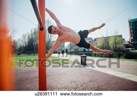 Calisthenics at outdoor gym, bare chested young man swinging horizontally on exercise equipment View Large Photo Image Stock Image - Calisthenics at outdoor gym, bare chested young man swinging horizontally on exercise equipment. Fotosearch
