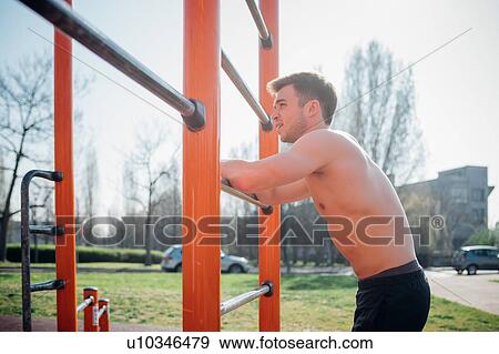 Calisthenics at outdoor gym, bare chested young man leaning on exercise equipment taking a break View Large Photo Image Stock Photo - Calisthenics at outdoor gym, bare chested young man leaning on exercise equipment taking a break. Fotosearch