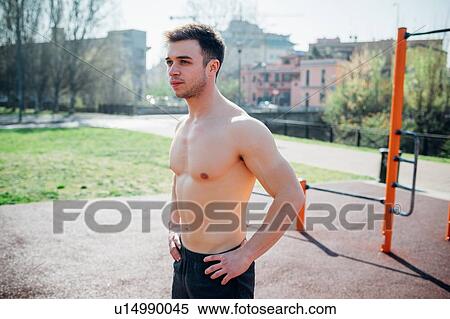 Stock Photography - Calisthenics at outdoor gym, bare chested young man taking a break. Fotosearch