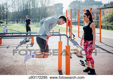 Calisthenics at outdoor gym, trainer watching young man on parallel bars View Large Photo Image Stock Photography - Calisthenics at outdoor gym, trainer watching young man on parallel bars. Fotosearch