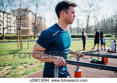 Picture - Calisthenics at outdoor gym, young man preparing to use parallel bars. Fotosearch
