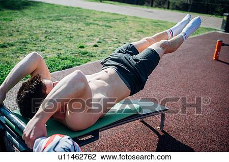 Calisthenics at outdoor gym, young man on weights bench with legs raised View Large Photo Image Stock Image - Calisthenics at outdoor gym, young man on weights bench with legs raised. Fotosearch