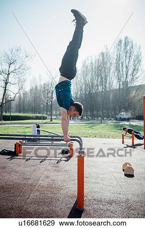 Stock Photo - Calisthenics at outdoor gym, young man doing handstand on parallel bars. Fotosearch
