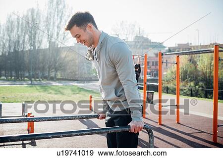 Stock Photo - Calisthenics at outdoor gym, young man on parallel bars. Fotosearch
