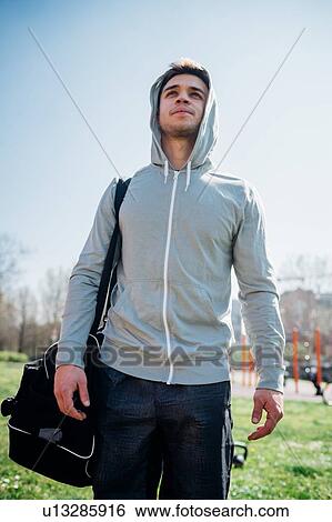 Stock Photograph - Calisthenics at outdoor gym, young man carrying sports bag. Fotosearch