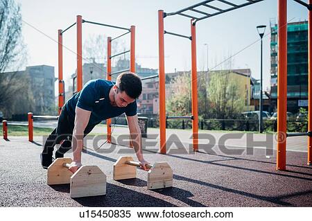 Calisthenics at outdoor gym, young man doing push ups on exercise equipment View Large Photo Image Stock Photography - Calisthenics at outdoor gym, young man doing push ups on exercise equipment. Fotosearch