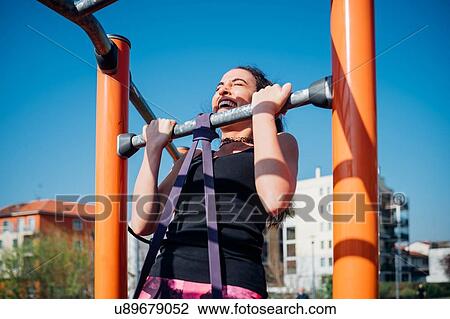 Calisthenics at outdoor gym, young woman doing pull up on exercise equipment View Large Photo Image Stock Image - Calisthenics at outdoor gym, young woman doing pull up on exercise equipment. Fotosearch
