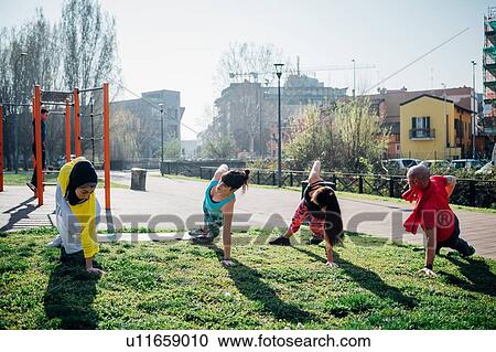Stock Image - Calisthenics class at outdoor gym, man and women practicing sideways yoga position. Fotosearch