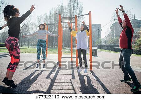 Stock Image - Calisthenics class at outdoor gym, man and women jumping. Fotosearch