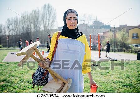 Picture - Calisthenics class at outdoor gym, young woman carrying exercise equipment. Fotosearch