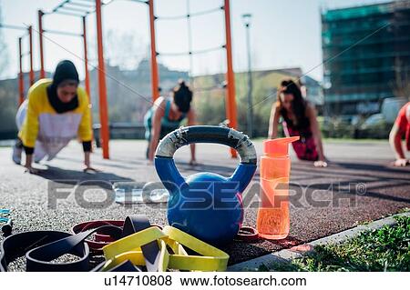 Stock Photo - Calisthenics class at outdoor gym, young women practicing yoga position, shallow focus. Fotosearch