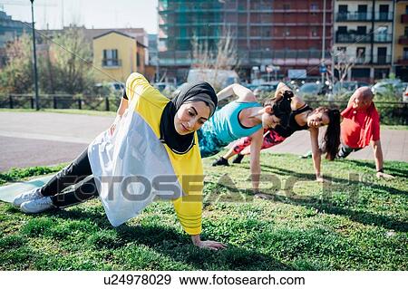 Stock Photo - Calisthenics class at outdoor gym, women and man practicing sideways yoga position. Fotosearch