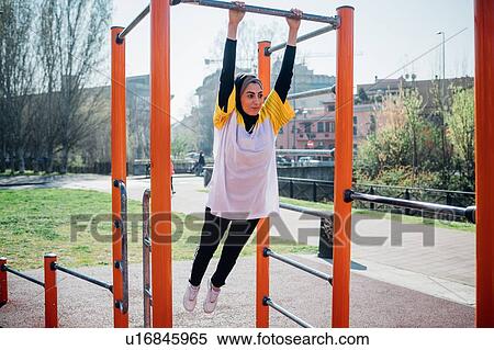Calisthenics class at outdoor gym, young woman swinging from exercise equipment View Large Photo Image Stock Photography - Calisthenics class at outdoor gym, young woman swinging from exercise equipment. Fotosearch