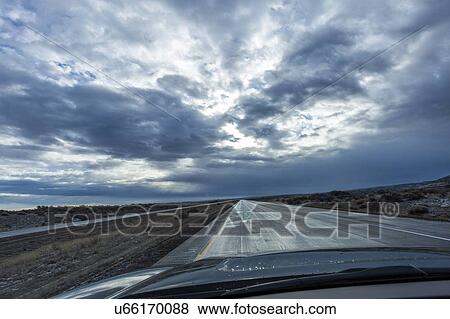 Stock Photo - Car on country road under overcast sky. Fotosearch
