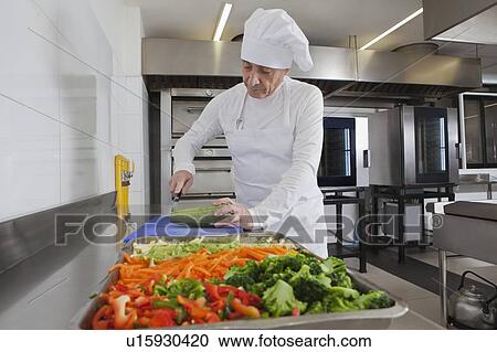 Chef slicing squash in commercial kitchen View Large Photo Image Stock Image - Chef slicing squash in commercial kitchen. Fotosearch
