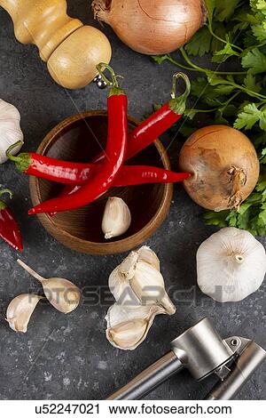 Stock Image - Chili peppers with garlic, onion and pepper mill. Fotosearch