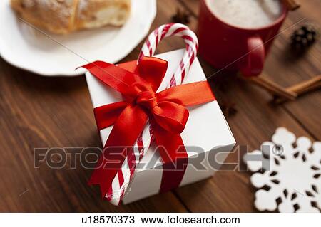 Stock Image - Christmas present with red ribbon and candy cane. Fotosearch