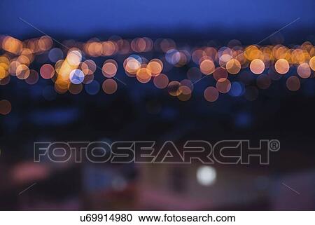 Stock Image - City lights in distance, blurred image.. Fotosearch