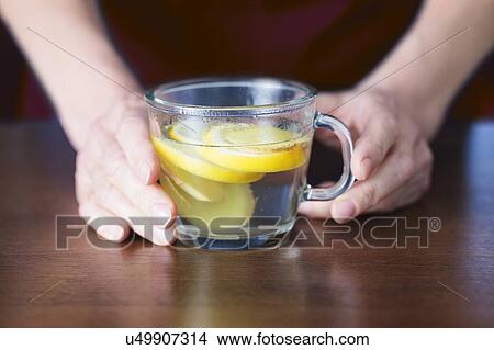 Close-up of hands holding lemon and ginger tea. View Large Photo Image Picture - Close-up of hands holding lemon and ginger tea.. Fotosearch