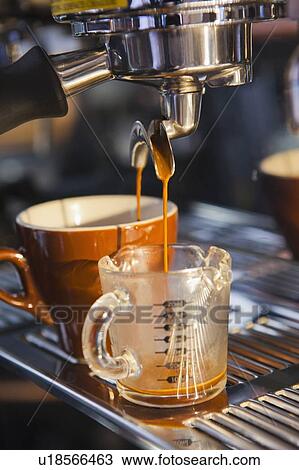 Stock Image - Coffee pouring from portafilter into coffee cup and beaker. Fotosearch