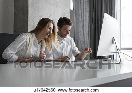 Colleagues laughing at desk View Large Photo Image Stock Image - Colleagues laughing at desk. Fotosearch