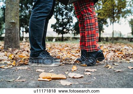 Stock Photo - Couple face to face in autumn park, surface level view of legs. Fotosearch
