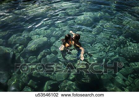 Stock Image - Couple kiss while swimming in sea. Fotosearch