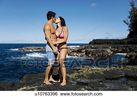 Stock Photograph - Couple kissing on rocks by sea. Fotosearch