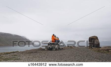 Stock Image - Couple sitting on picnic table. Fotosearch