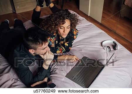 Stock Photo - Couple using laptop on bed. Fotosearch