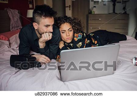 Couple using laptop on bed View Large Photo Image Stock Photograph - Couple using laptop on bed. Fotosearch