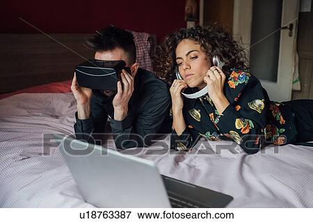 Couple using VR headset and laptop on bed View Large Photo Image Stock Photo - Couple using VR headset and laptop on bed. Fotosearch