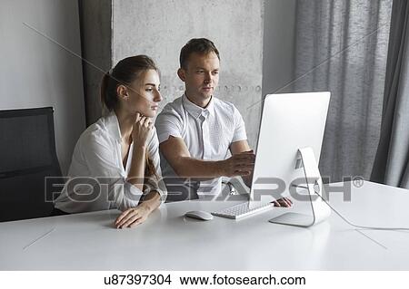 Picture - Coworkers working together at desktop computer. Fotosearch